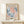 May include: Framed vintage-style exhibition poster featuring Matisse's cut-paper artwork in coral pink and blue organic flowing shapes against cream background, displayed on light wood console table beside small wrapped gift with greenery accent on white wall