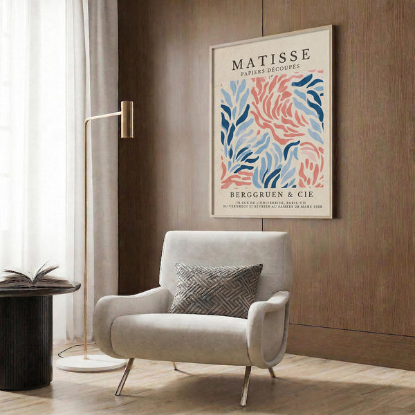 a living room with a white armchair, a floor lamp, and a framed poster of a colorful abstract painting hanging on the wall.