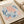The image is a framed poster featuring the work of the artist M.C. Escher. The poster displays a colorful abstract pattern in shades of blue, pink, and orange, along with the text "M.C. Escher" and "Papiers Découpe". The poster also includes the text "Bergruen & Cie" and "70 Rue de l'Université de Samedi, Paris 28 March 1958".