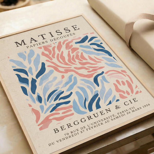 The image is a framed poster featuring the work of the artist M.C. Escher. The poster displays a colorful abstract pattern in shades of blue, pink, and orange, along with the text "M.C. Escher" and "Papiers Découpe". The poster also includes the text "Bergruen & Cie" and "70 Rue de l'Université de Samedi, Paris 28 March 1958".