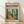 May include: Framed art poster featuring a colorful indoor scene with tropical plants, yellow chair, and bright interior space in Matisse's distinctive style. The cream-colored poster displays "matisse modernist" text at top and "Embracing Colorful Freedom In The Spirit of Matisse" at bottom. Natural wood frame leans against white wall on light wooden floor with soft shadows.