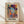 May include: Framed poster print featuring a vibrant portrait of a woman wearing a decorative hat, rendered in bold geometric patterns with teal, orange, purple, and yellow colors. The artwork combines modernist style with intricate textile-like designs and includes "MATISSE" text at bottom. Light wood frame sits against white wall on natural wood flooring with soft natural lighting creating diagonal shadows.