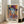 May include: Framed colorful portrait poster of a woman wearing a hat, displayed in bright living room setting next to beige sectional sofa. Artwork features vibrant blues, oranges, yellows and geometric patterns in modernist style with "MATISSE" text at bottom. Natural wood frame, hardwood floors, white walls with large windows showing daylight.
