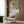 May include: Matisse-inspired poster with colorful botanical artwork featuring orange vase with green foliage, geometric shapes in terracotta and sage tones, displayed in modern living room with beige armchair, gold floor lamp, and wood paneled wall