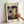 May include: Hands holding a framed art print featuring Paul Klee's abstract artwork with colorful geometric shapes, watercolor-like washes in blues, reds, yellows, and earth tones, plus intricate line drawings. The print shows "KUNSTMUSEUM BASEL - 1914" at bottom. Light wood frame against white background with soft natural lighting creating gentle shadows.
