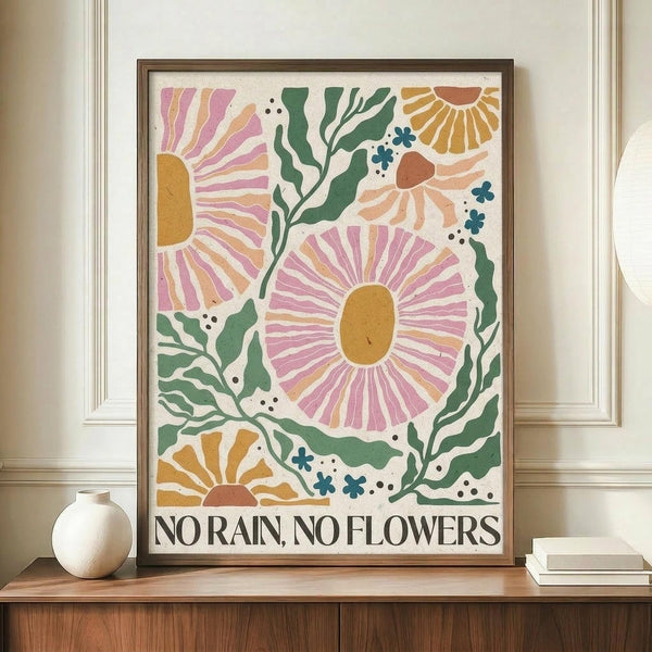 May include: Framed botanical art print with colorful abstract flowers in pink, orange, and yellow with green foliage on cream background, displaying "NO RAIN, NO FLOWERS" text at bottom. Print sits on wooden sideboard next to white ceramic vase and books in elegant room with beige walls and white trim molding.