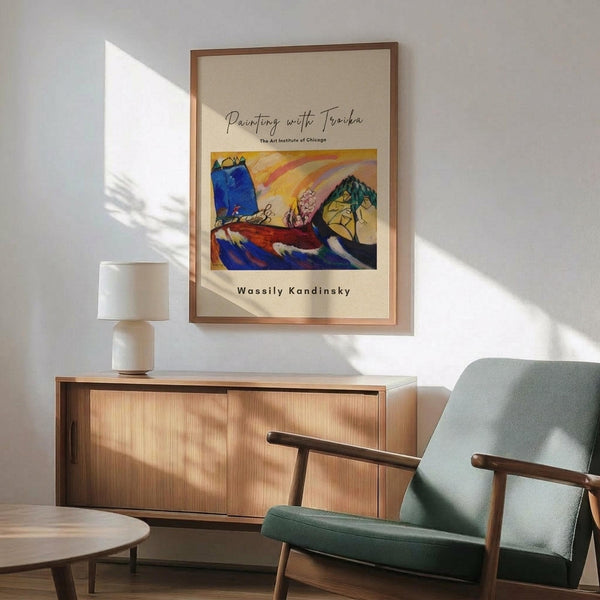 May include: Framed art print featuring Wassily Kandinsky's abstract expressionist painting with vibrant blues, yellows, reds and greens in flowing organic forms. Displayed above mid-century modern wooden credenza with white ceramic lamp. Sage green upholstered armchair with wooden frame sits nearby. Natural sunlight creates geometric shadows on white wall in minimalist living room setting.