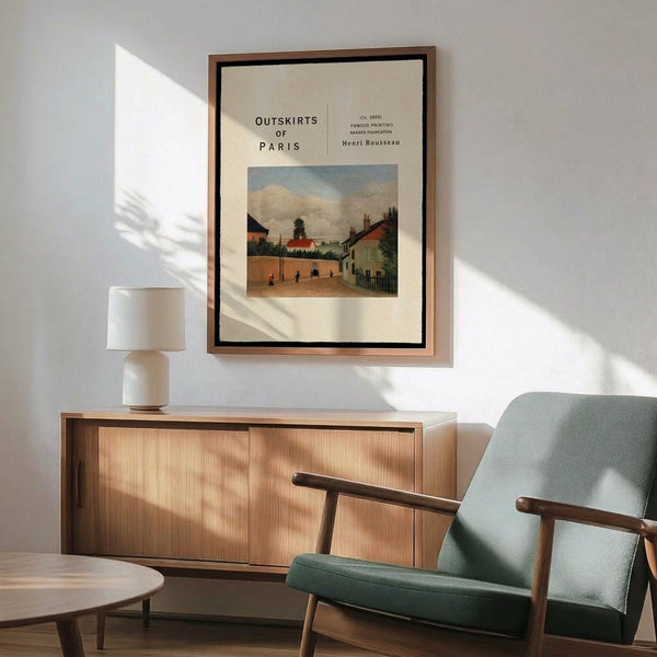 May include: Framed vintage art print featuring a pastoral village scene with houses, trees, and small figures on a dirt road under cloudy skies. The cream-colored poster with black text is displayed above a mid-century modern wood sideboard with ceramic lamp, next to a mint green upholstered armchair with wooden frame in a sunlit room.