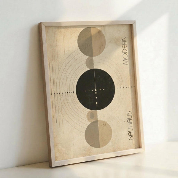 Framed geometric art print featuring three circles arranged vertically - two muted beige circles and one dark green circle in the center. The design includes curved concentric lines radiating from the left side and a dotted line extending horizontally through the middle circle. Text reading "MODERN" appears vertically on the right side and "BAUHAUS" on the bottom right. The artwork is displayed in a light wooden frame against a white wall, showing natural lighting and shadows.