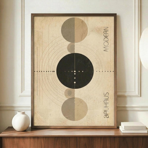 May include: Framed geometric poster with cream background featuring vertical arrangement of circles in sage green, tan, and dark forest green. Design includes concentric lines, dots, and "MODERN" and "BAUHAUS" text. Wood frame displayed on walnut credenza beside white ceramic vase and stacked books in elegant room with white wainscoting.
