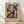 May include: Framed abstract artwork poster leaning against white wall on light wood flooring. The piece features geometric rectangular patches in muted colors including blues, purples, greens, pinks, and earth tones arranged in a mosaic-like pattern. Text reads "Exhibition Art - 1914" at top and "About a Motif from Hammamet - Kunstmuseum Basel Museum" and "Paul Klee" at bottom on beige background. Natural lighting creates soft shadows on the wall.