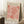 May include: Framed art print leaning against white wall corner next to coffee cup on wooden block and textured throw blanket. The poster features coral pink organic leaf-like cutout shapes on cream background with "MATISSE" at top and "PAPIERS DÉCOUPÉS" at bottom in black text. Natural wood frame, displayed on white fluffy rug with soft window lighting creating shadows on wall.