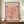 May include: Framed art print featuring coral-pink organic leaf-like shapes in Matisse's paper cut-out style against cream background, displayed on wooden sideboard next to white ceramic vase and stacked books in elegant room with white paneled walls