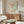 May include: Framed Matisse art print displayed above wooden sideboard in modern living room. Poster features colorful abstract cut-out shapes in pink, green, and white with black polka dot patterns. Room shows cream textured chair, glass oval coffee table, white table lamp, and neutral walls with natural lighting.