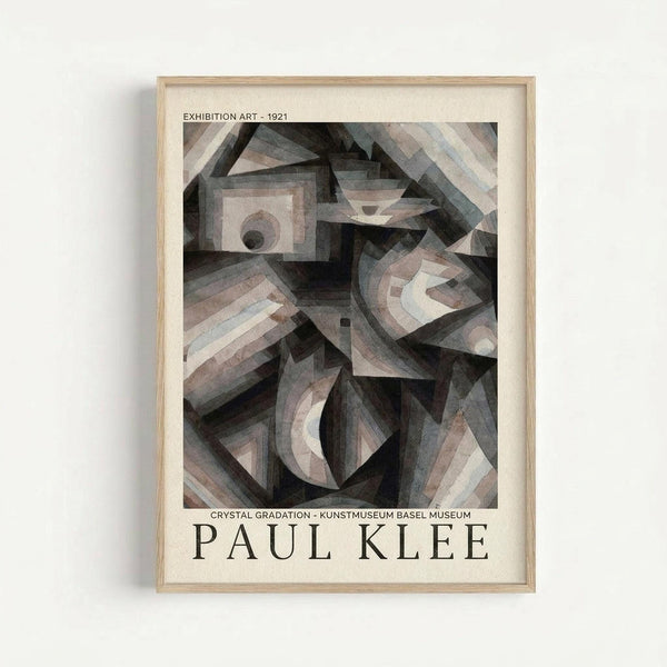 May include: Framed exhibition poster featuring Paul Klee's abstract geometric artwork from 1921 in muted tones of gray, brown and cream. The cubist-style composition shows angular, overlapping shapes and forms creating depth and movement. Displayed in a natural wood frame against a light background, showing museum exhibition details and the artist's name in bold text below the artwork.