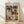 May include: Framed poster print featuring Paul Klee's abstract geometric artwork with colorful triangular shapes at top and architectural forms below in blues, yellows, greens, and earth tones. Natural wood frame against white wall on light wooden floor with soft shadows from window light.
