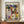 May include: Paul Klee abstract artwork print in brown wooden frame, displayed on walnut sideboard against cream wall with decorative molding. The colorful geometric composition features overlapping houses, triangular roofs, and architectural forms in blues, yellows, oranges, and earth tones. Small white ceramic vase and stacked books sit alongside the framed print.