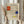 May include: Person in cream ruffled sleeve top holding framed Mondrian-style art print with geometric grid pattern featuring red, blue, and yellow rectangular blocks on beige background. Natural dried wheat stems visible alongside. Soft neutral lighting and white curtains in background create minimalist aesthetic.