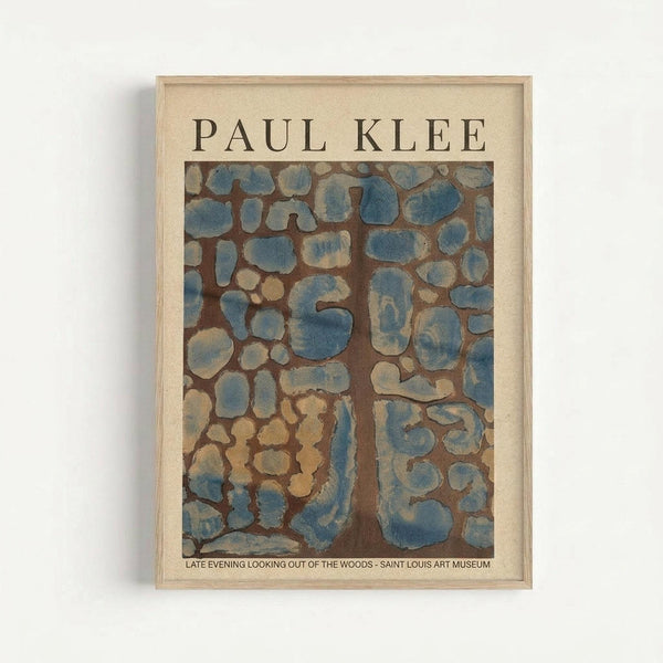 May include: Framed Paul Klee art print hanging on white wall in light wood frame. Abstract artwork features organic blue and beige shapes resembling stones or cells against brown background. Museum exhibition poster with cream matting and clean modern presentation.