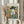 May include: Person in cream ruffled sleeves holding framed Picasso-style portrait poster and dried wheat stems against white curtained window. Artwork shows figure in dark hat and blue clothing with geometric colorful background in cubist style. Light wood frame, soft natural lighting.