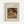 May include: Framed art print displaying a Pierre Auguste Renoir painting of a young child with reddish-brown hair reading a book. The child wears a light-colored dress and is shown in Renoir's characteristic soft, impressionistic style with warm tones. The print features cream matting with black text identifying the artist and subject, housed in a natural wood frame against a white wall.