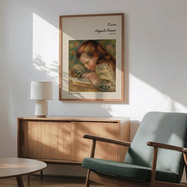 May include: Framed Renoir reproduction poster showing a young child with reddish hair reading a book, displayed above a wooden sideboard with table lamp in a modern living room setting with mint green armchair, natural lighting creating wall shadows