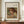 May include: Framed art print of Pierre Auguste Renoir painting showing young child with reddish-brown hair reading a book, rendered in soft impressionist brushstrokes with warm earth tones. Print displayed on wooden sideboard next to white ceramic vase and stacked books in elegant room with cream walls and white trim molding.