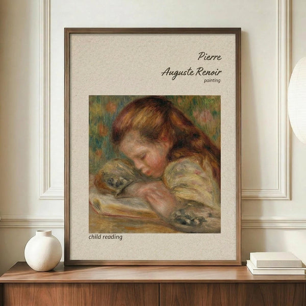 May include: Framed art print of Pierre Auguste Renoir painting showing young child with reddish-brown hair reading a book, rendered in soft impressionist brushstrokes with warm earth tones. Print displayed on wooden sideboard next to white ceramic vase and stacked books in elegant room with cream walls and white trim molding.