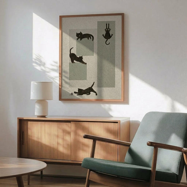 May include: Framed poster showing four black cat silhouettes in different playful poses on sage green and cream geometric background, displayed above wooden sideboard with white ceramic lamp in modern living room with mint green mid-century armchair and natural sunlight casting shadows on white wall.