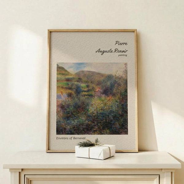 May include: Framed art print featuring Pierre Auguste Renoir's impressionist landscape painting of rolling hills and countryside around Berneval, displayed on light wood console table with small white gift box tied with evergreen sprig, set against cream wall with natural lighting