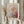 May include: Person holding framed art poster featuring abstract botanical design with pink circular forms, green stem, and colorful dotted pattern background. Light wood frame against white curtained window, dried wheat stems visible on left side.