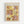 May include: Framed Paul Klee exhibition poster displayed on white wall in light wooden frame. Abstract artwork features warm earth tones of yellow, brown, pink and cream in geometric blocks with botanical and figurative line drawings including plants, human forms, and architectural elements. Museum poster format with artist name at top and exhibition details at bottom.