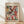 May include: Framed Paul Klee abstract art print featuring colorful geometric squares and rectangles in red, green, violet, yellow, and blue tones with small plant motifs scattered throughout. The poster has museum text at bottom and is displayed in a light wood frame against white walls on wooden floors with natural window lighting casting shadows.