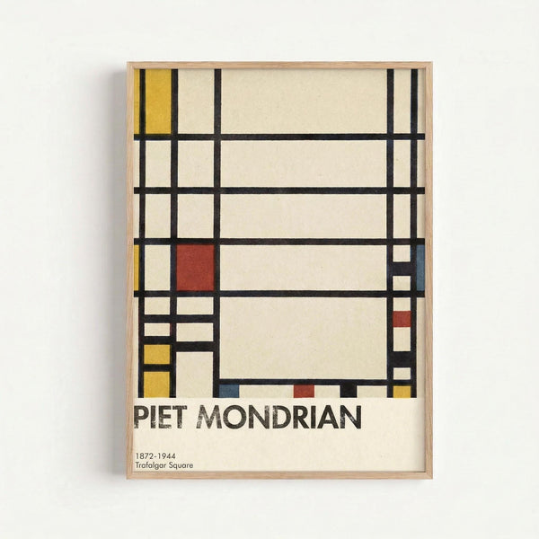 Abstract geometric composition with black grid lines creating rectangular sections filled with primary colors including yellow, red, and blue blocks against cream and white backgrounds. The artwork is displayed as a framed print with light wood frame against a white wall, featuring the artist's name and dates 1872-1944 with "Trafalgar Square" text below the geometric design.