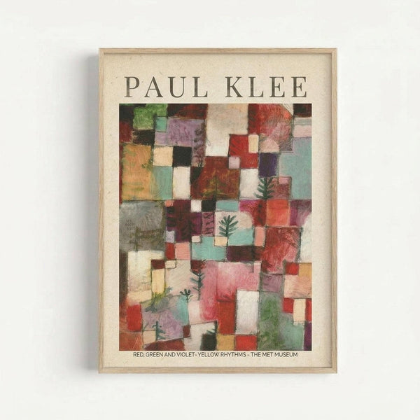 May include: Framed museum poster featuring Paul Klee's abstract geometric artwork with colorful squares and rectangles in red, green, purple, yellow, and turquoise tones. Small evergreen tree motifs scattered throughout the composition. Light wood frame with cream matting against white wall. Text reads "Red, Green and Violet - Yellow Rhythms - The Met Museum" below the artwork.