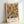 May include: Abstract expressionist poster print in light wood frame, featuring energetic composition of orange, blue, yellow, and green paint splatters with black lines and dots against cream background. Text reads "POLLOCK Expressive Expressionist Movement" at bottom. Frame leans against white wall on light surface, showing natural wood grain and white matting around colorful drip painting reproduction.