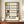 May include: Framed Mondrian abstract art print with geometric black grid lines and yellow, red, and blue color blocks on cream background, displayed on wooden sideboard next to white ceramic vase and stacked books in elegant room with white paneled walls