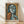 May include: Framed poster print in light wood frame leaning against white wall on wooden floor. Abstract cubist-style portrait featuring geometric figure with stylized face in blues, oranges, and earth tones. French text at bottom reads "Art contemporain inspiré par un maitre artistique" and "PICASSO". Soft natural lighting creates diagonal shadows across white textured wall.