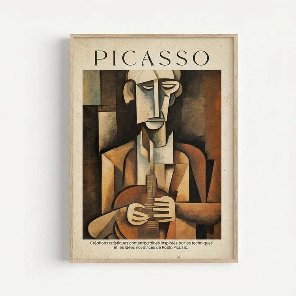 May include: Framed Picasso-style cubist poster showing geometric figure holding guitar in earth tones of brown, tan, and orange. Abstract portrait features fragmented face and angular body composed of intersecting planes. French text below artwork. Natural wood frame against white wall with soft shadow.