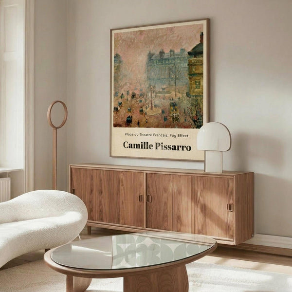 May include: Vintage-style art poster of Parisian street scene with buildings and figures in muted tones, displayed in thin frame above walnut wood credenza. Modern living room setting with cream curved chair, glass oval coffee table, and minimalist decor in neutral beige and wood tones.
