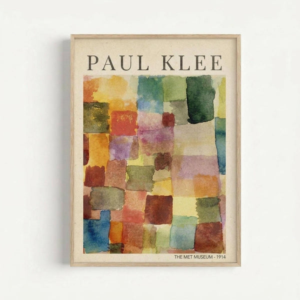 May include: Framed Paul Klee watercolor reproduction print hanging on white wall, featuring abstract geometric squares and rectangles in soft watercolor washes of yellow, orange, red, purple, green, and blue. The artwork shows Klee's characteristic translucent color blocking technique with overlapping painted shapes. Natural wood frame surrounds cream-colored mat with "PAUL KLEE" text at top and "THE MET MUSEUM - 1914" at bottom.