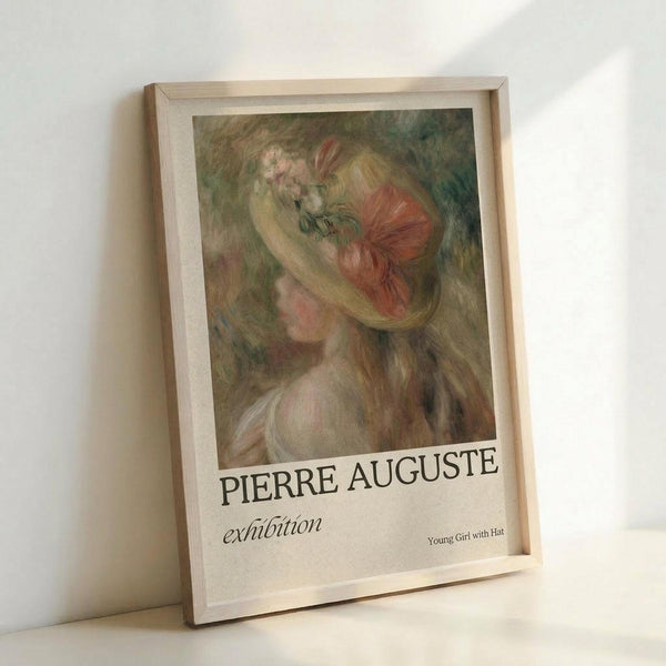 May include: Framed exhibition poster featuring a soft, impressionistic painting of a young woman with long blonde hair wearing a red hat with floral details. The artwork shows gentle brushstrokes in warm tones of pink, green, and coral against a muted background. The poster displays "PIERRE AUGUSTE exhibition" text below the image with "Young Girl with Hat" in smaller text. Light wood frame rests against white wall on white surface, creating subtle shadows.