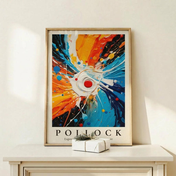 May include: Abstract expressionist artwork poster in light wood frame on white shelf beside small wrapped gift. Painting features explosive radial composition with orange, red, yellow, blue, and black paint streaks radiating from white center with red circle. Dynamic splashes, drips, and circular dots create energetic movement. White wall background, minimal modern interior setting.