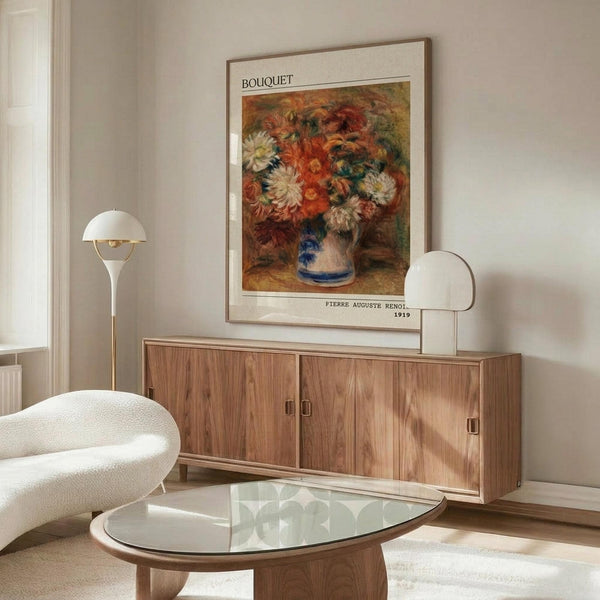 May include: Warm wood sideboard with white table lamp and framed vintage floral poster showing orange and white chrysanthemums in blue-striped vase. Modern living room setting features cream sculptural chair, glass oval coffee table, and neutral walls. Poster displays in thin wood frame above mid-century furniture.