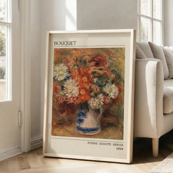 May include: Framed art print of Renoir's impressionist flower painting showing vibrant orange, red, and white blooms in a blue and white ceramic vase. The poster features "BOUQUET" at top and "PIERRE AUGUSTE RENOIR 1919" at bottom on cream background with thin wooden frame, leaning against white wall next to beige upholstered chair in bright, naturally lit room with hardwood floors.