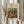 May include: Hands holding a framed reproduction of Renoir's impressionist painting showing figures in a pastoral scene with warm oranges, greens, and earth tones. The artwork is displayed in a light wood frame with cream matting against soft white curtains, alongside dried wheat stalks for styling.