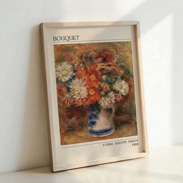 May include: Framed art print leaning against white wall showing impressionist painting of colorful flower bouquet in blue and white striped vase. Artwork features vibrant orange, red, white and yellow blooms with loose brushstrokes in warm, golden tones. Print has white border with "BOUQUET" at top and "PIERRE AUGUSTE RENOIR 1919" at bottom, displayed in light wooden frame.