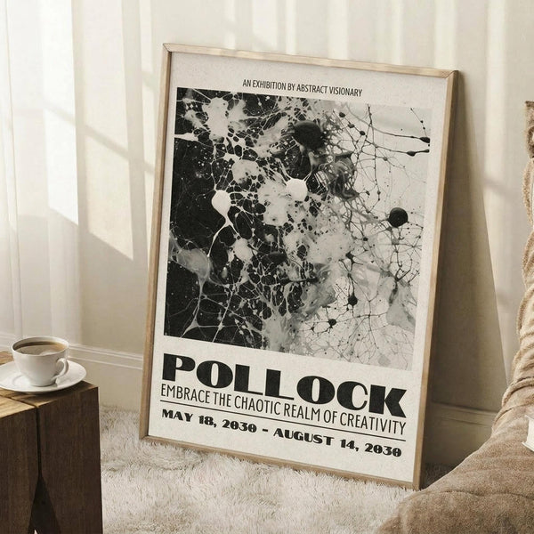 May include: Black and white abstract art poster with paint splatters and cracked textures, displayed in light wood frame leaning against white wall. Exhibition-style design with bold typography reading "POLLOCK" and "EMBRACE THE CHAOTIC REALM OF CREATIVITY" with dates May 18, 2030 - August 14, 2030. Room setting shows white coffee cup on wooden block and beige textured throw blanket on light wood floor.