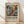 May include: Framed abstract art poster featuring vibrant swirling brushstrokes in blues, yellows, oranges, and reds with chaotic paint splatters, displayed in light wood frame against white wall on wooden floor with natural lighting creating soft shadows