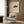 May include: Vintage-style poster featuring detailed illustration of radiated tortoise with geometric shell pattern in brown and yellow tones, displayed in light wooden frame against wood panel wall, shown with beige upholstered armchair, geometric patterned throw pillow, brass floor lamp, and dark round side table in modern neutral living room setting